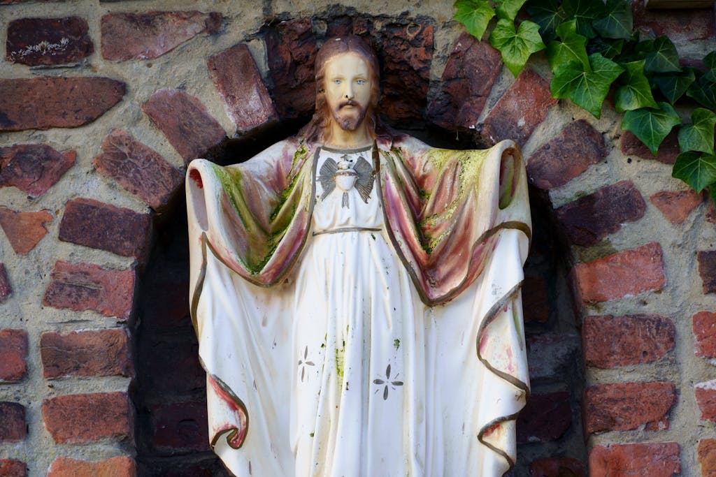 A statue of jesus is in front of a brick wall